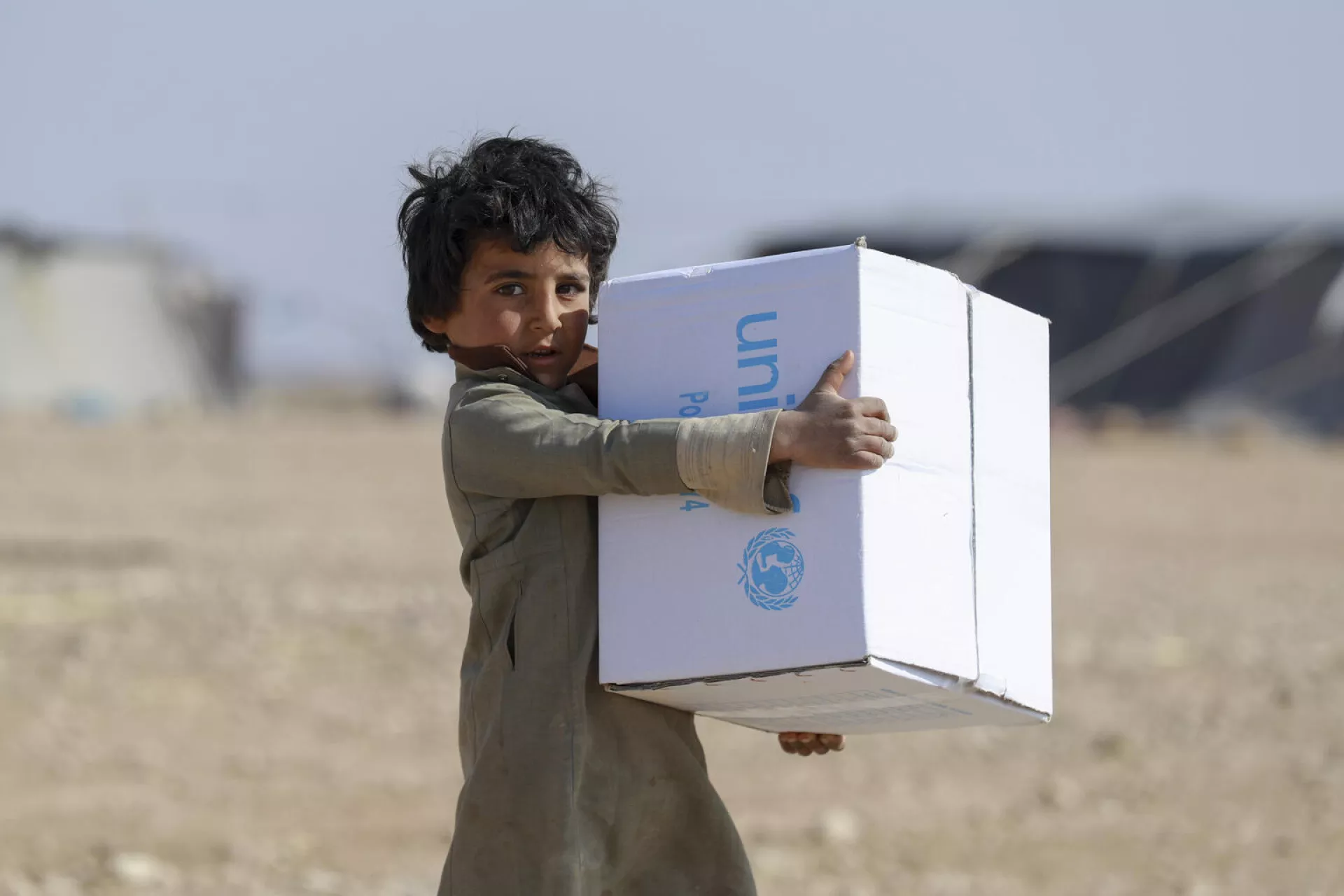 Syria. An internally child carries a box of UNICEF-provided supplies.
